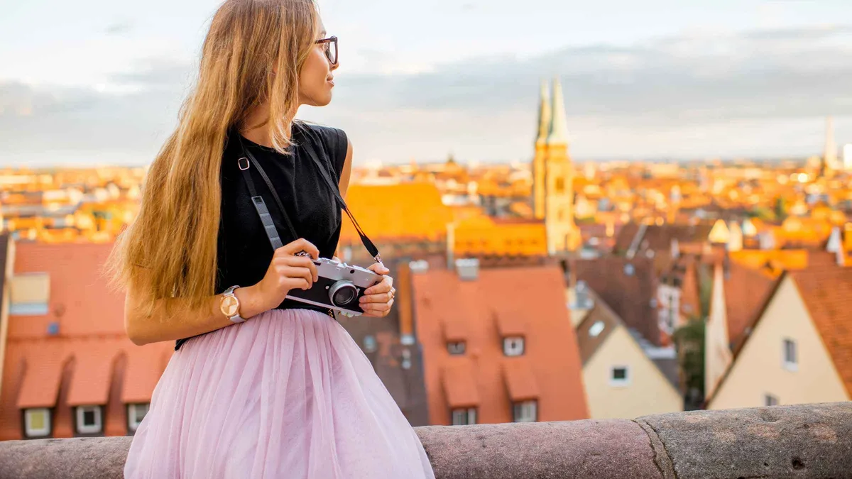 A traveler holding a camera on a terrace above the red roofs of Nuremberg's old town