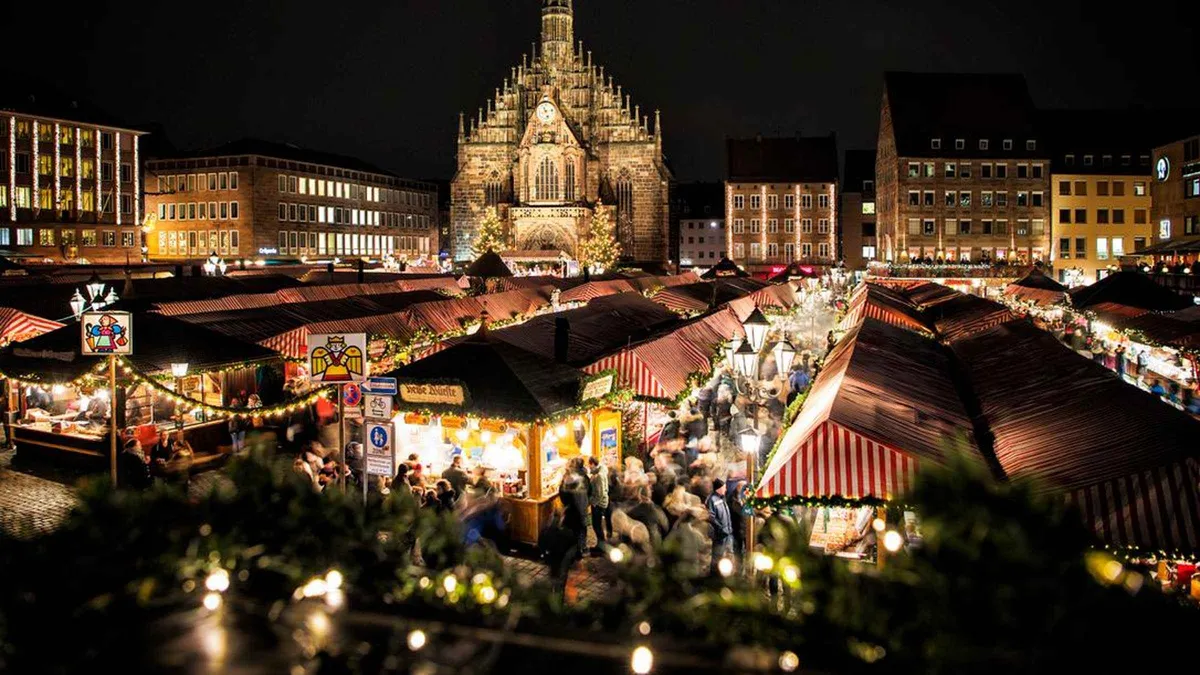 Lit market stalls on the Hauptmarkt at night with the Frauenkirche facade behind