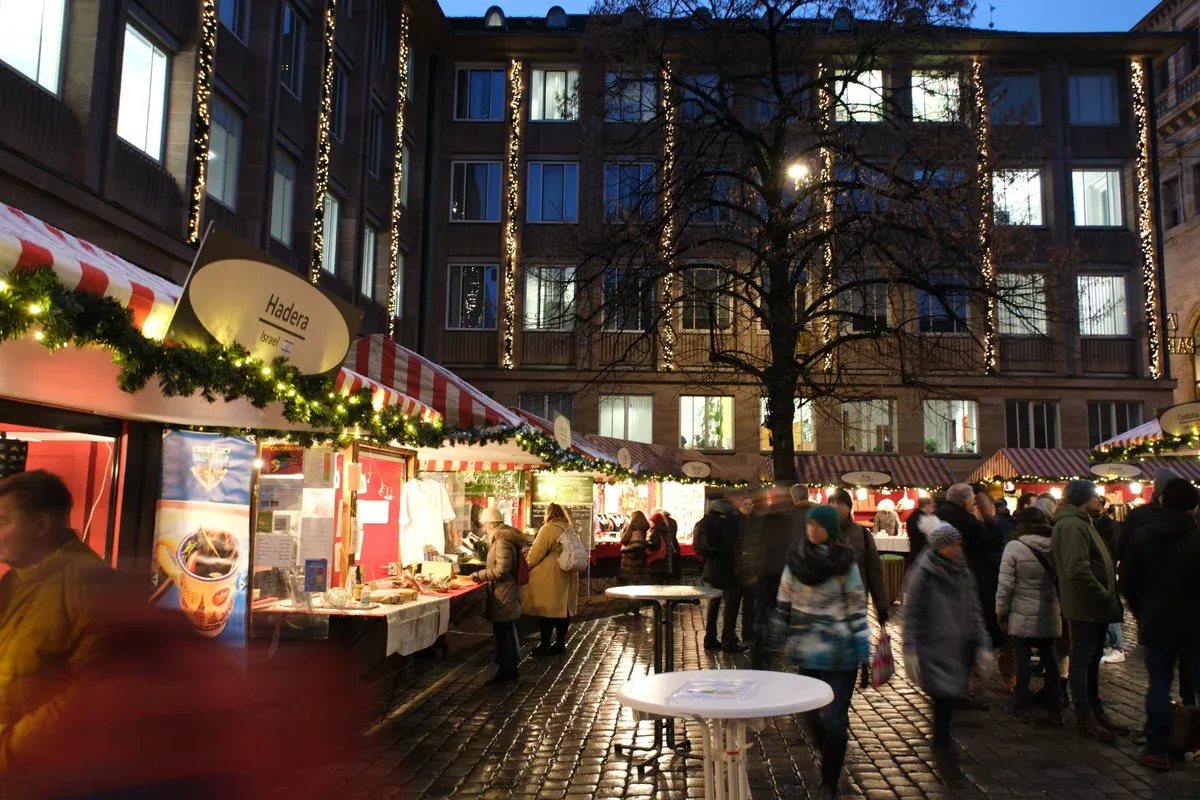 Lit stalls of the Market of the Sister Cities on Rathausplatz on a wet December evening